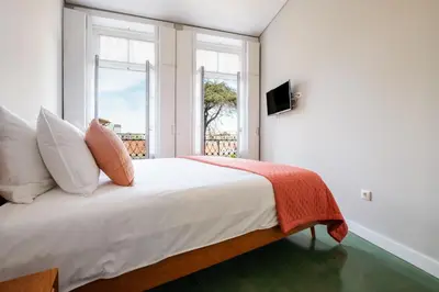 a bedroom with a bed with white sheets and a window at Alegria Colour Apartments in Porto