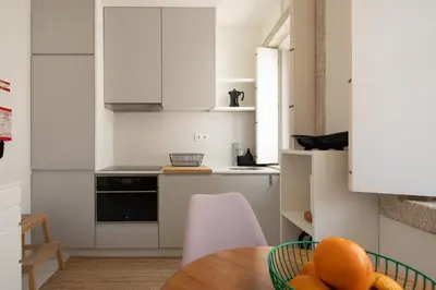 a kitchen with white cabinets and a wooden table at Cosy Minimalist duplex in Porto
