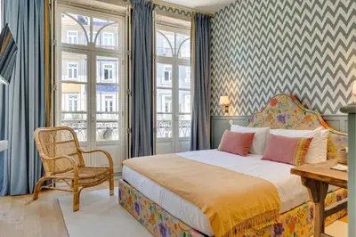 a bedroom with a bed and a chair and windows at Lóios 74 Suites by DA'HOME in Porto
