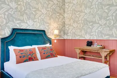 a bedroom with a bed with a blue headboard and a table at Lóios 74 Suites by DA'HOME in Porto