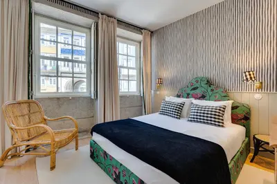 a bedroom with a bed and a chair and a window at Lóios 74 Suites by DA'HOME in Porto