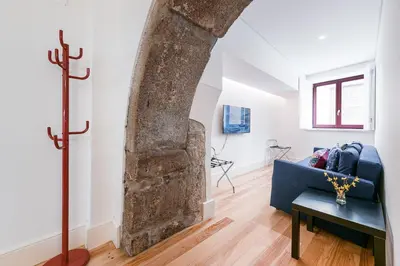 a living room with a stone pillar and a blue couch at GuestReady - Arcos da Ribeira in Porto