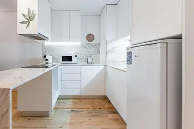 a kitchen with white cabinets and a refrigerator at GuestReady - Arcos da Ribeira in Porto