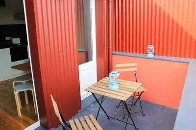 a small table and chairs in a kitchen with an orange wall at Oporto Trendy Apartments in Porto