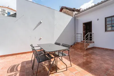 a table and chairs on a patio with a white wall at GuestReady - Sunny Stay in Porto City Center in Porto