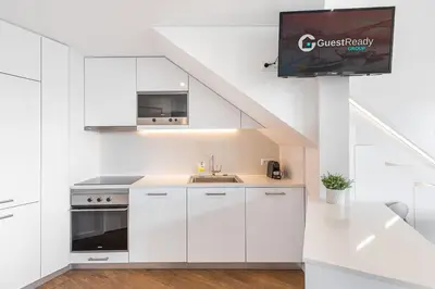 a kitchen with white cabinets and a tv on a wall at GuestReady - Riverview Douro Terrace in Vila Nova de Gaia