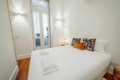 a white bedroom with a large white bed and a window at Home With a Pool by Vacationy in Porto