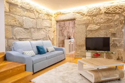 a living room with a blue couch and a stone wall at Casa do Vasco in Porto
