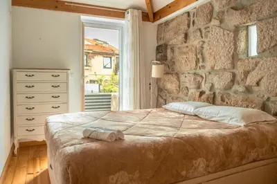 a bedroom with a large bed and a stone wall at Casa do Vasco in Porto