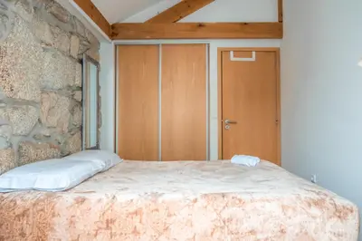 a bedroom with a bed and a stone wall at Casa do Vasco in Porto