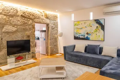 a living room with a blue couch and a stone wall at Casa do Vasco in Porto
