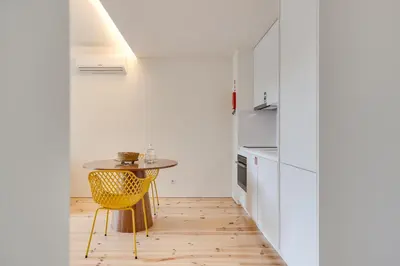 a kitchen with a small table and a yellow chair at Alma da Casa by DA'HOME in Porto
