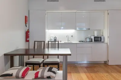 a kitchen with white cabinets and a table and chairs at Capim Dourado Apartments Cedofeita in Porto