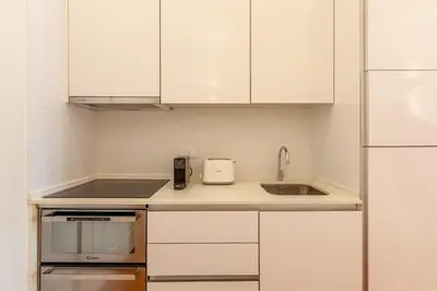 a kitchen with white cabinets and a sink at D&S - Alvares Cabral in Porto