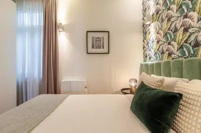 a bedroom with a white bed with a green headboard at D&S - Alvares Cabral in Porto