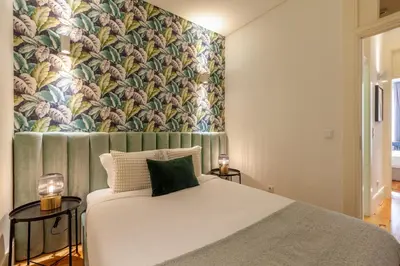 a bedroom with a white bed with a floral wallpaper at D&S - Alvares Cabral in Porto