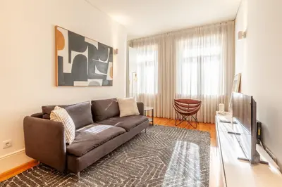 a living room with a brown couch and a television at D&S - Alvares Cabral in Porto