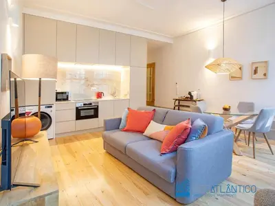 a living room with a blue couch and a kitchen at Porto Almada Design Loft in Porto