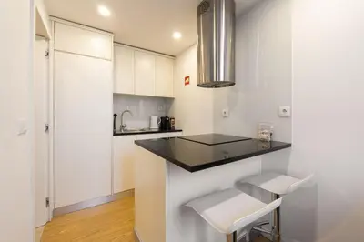 a kitchen with white cabinets and a counter and stools at GuestReady - King House 2 in Porto