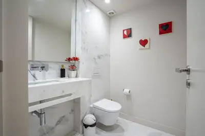 a white bathroom with a toilet and a sink at Primrose 1BR Delight w Parking by LovelyStay in Porto