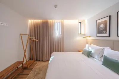 a bedroom with a large white bed and a window at Feel Porto Firmeza Coworking & Flats in Porto