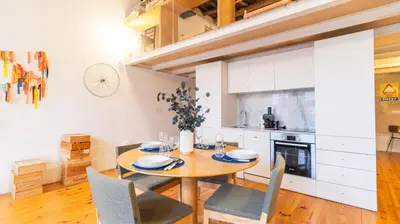 a kitchen and dining room with a wooden table and chairs at Eccentric Mouzinho Mezzanine by LovelyStay in Porto