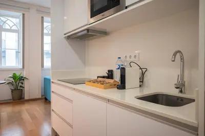a kitchen with white cabinets and a sink at Santa Catarina Charm Apartment Downtown near Metro in Porto