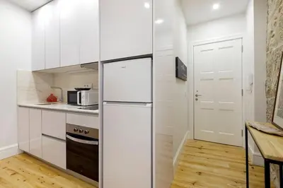 a kitchen with white cabinets and a refrigerator at Oporto Lovely Apartment in Porto
