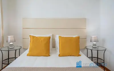 a bedroom with a bed with yellow pillows and two tables at Porto Sé Classic Terrace Apartment in Porto