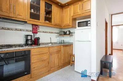a kitchen with wooden cabinets and a white refrigerator at Porto Sé Classic Terrace Apartment in Porto