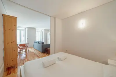 a white bedroom with a bed and a living room at Cozy Almada by Hosty in Porto