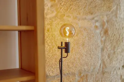 a light bulb on a wall with a stone wall at Cozy Almada by Hosty in Porto
