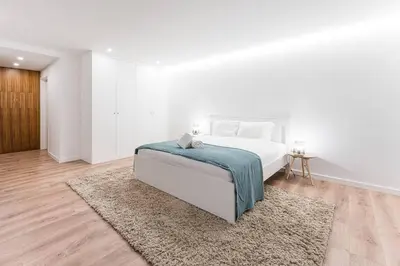 a white bedroom with a bed and a rug at Porto Paraíso Right by RDC in Porto