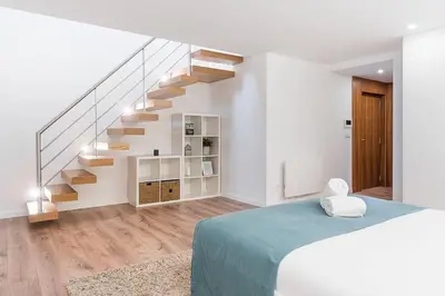 a white room with a staircase and a bed at Porto Paraíso Right by RDC in Porto