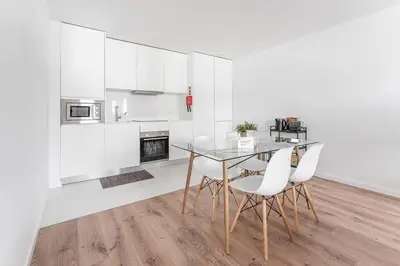 a kitchen with a glass table and white cabinets at Porto Paraíso Right by RDC in Porto