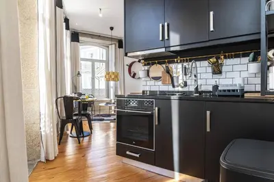 a kitchen with black cabinets and a stove top oven at Mouzinho Penthouse by Hosty in Porto