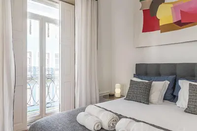 a bedroom with a large bed and a balcony at Mouzinho Penthouse by Hosty in Porto