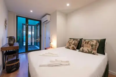 a bedroom with a bed with white sheets and a window at Exotic Flat with Shared Pool & Garden in Porto