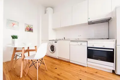a kitchen with white appliances and a table and chairs at Citybreak-apartments Sao Bento in Porto