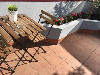 a patio with a table and chairs and flowers at Miguel Bombarda Cozy Apartment in Porto