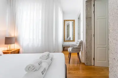 a white bedroom with two beds and a chair at GuestReady - Lovely heaven in Porto in Porto