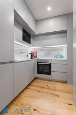 a kitchen with white cabinets and a wooden floor at Quinta da Boa Vista Garden & Terrace in Porto