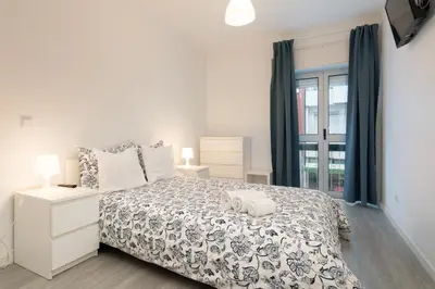 a white bedroom with a bed and a window at Moreira Terrace in Porto
