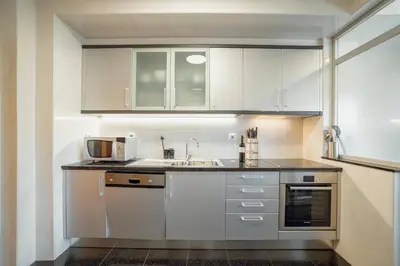a kitchen with white cabinets and a sink and a microwave at Boavista Premium by Hosty in Porto