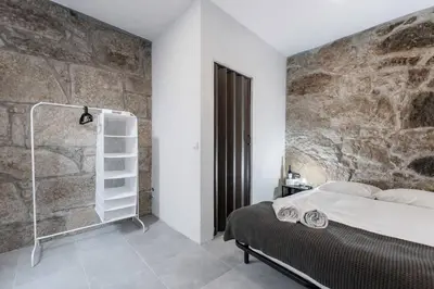a bedroom with a stone wall and a bed at PortoNest Downtown Suites in Porto