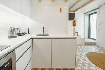 a white kitchen with a sink and a counter at Lapa Cozy by Hosty in Porto