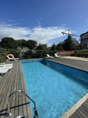 a swimming pool on a wooden deck with chairs at Cosy House Downtown Porto with swimming pool and AC in Porto