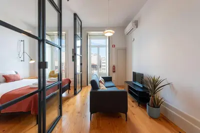 a kitchen and living room with white cabinets and a blue rug at São Bento Bright Studio in Porto