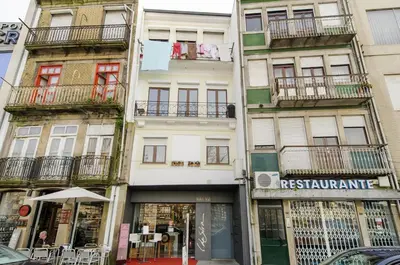 a tall white building with a restaurant in front of it at Douro River Apartments in Vila Nova de Gaia