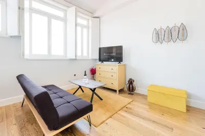a living room with a couch and a tv and a table at Frei Yellow Studio in Porto